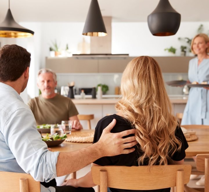 Family With Senior Parents And Adult Offspring Eating Meal Around Table At Home Together